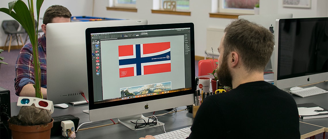 Whitespacepw graphic designer working at a computer designing a corporate brochure for ISS Norway