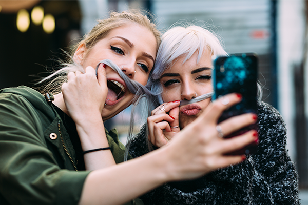 Whitespacepw: Marketing Millenials via Snapchat blog post cover, with a red and purple gradient background and Whitespacepw logo, and a faded image of two girls taking a selfie